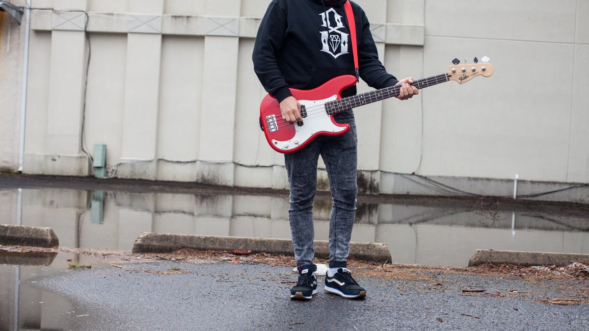  Viktor, an undocumented immigrant from Belarus seeking asylum in the U.S, strums a bass guitar. He left with bandmate Alexander and hopes to play music again if he is able to attain legal status. (Brad Larrison for NewsWorks) 