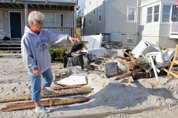 <p><p>Debbie Gutzler sorts through the debris deposited in the front yard of her home on Atlantic Avenue in Beach Haven, N.J. She suspects that much of it came from her neighbor's beach-front home. (Emma Lee/for NewsWorks)</p></p>
