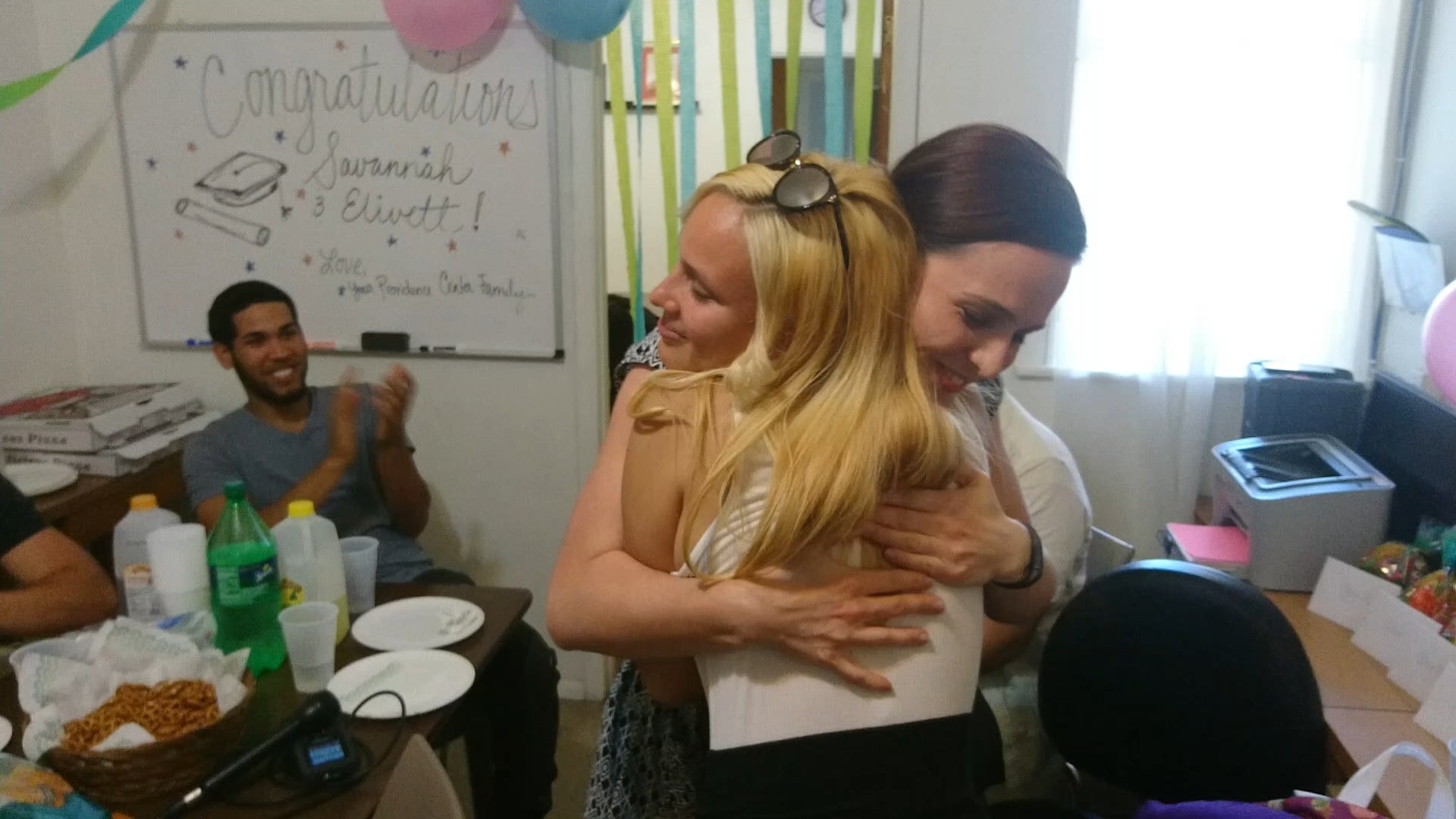 Slideshow: Savannah hugs Maura Bernt, Providence’s director of youth programs, at a party the non-profit threw to celebrate their graduating teen leaders. (Kevin McCorry/WHYY)