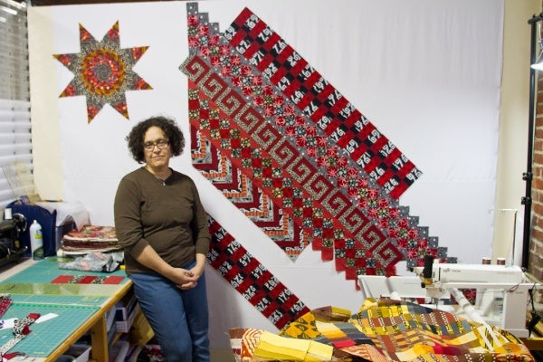 <p><p>Sarah Bond stands in the studio where she makes quilts in the Mt. Airy Art Garage. Bond has been quilting for 30 years and says it runs in the family. (Brad Larrison/for NewsWorks)</p></p>
