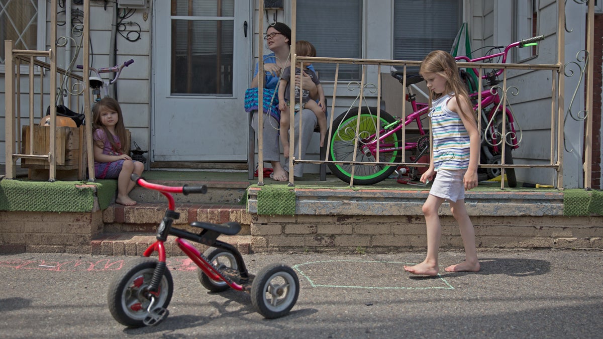  Heather Hoover sits on her porch while her children, Emmalie, 6, Hannah, 3, and Jared, 1, play in front of their home in Mahanoy City, Pennsylvania. Hoover, a mother of eight, hopes to move to a place with more space for her children to play. She said it seems like the town is falling apart. (Lindsay Lazarski/WHYY) 
