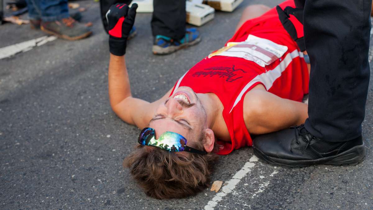 A runner collapses after crossing the finish line during the Philadelphia Marathon.