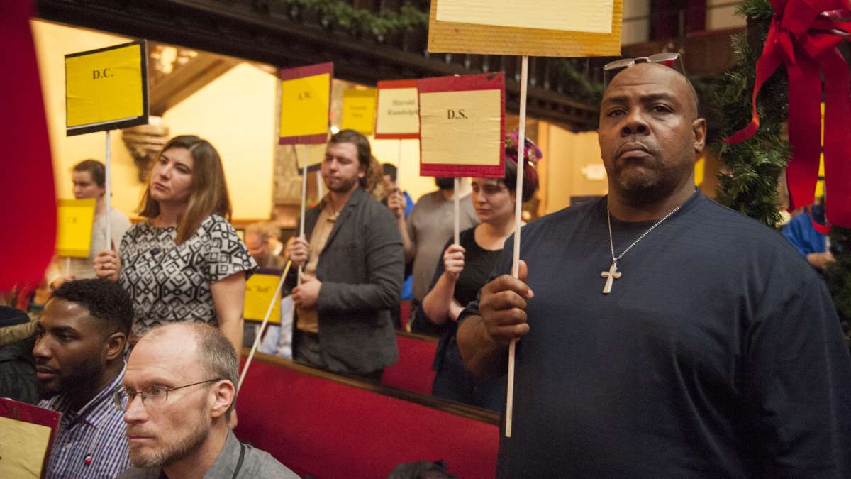 Pro Act Lead Coordinator Jerome Grause, and other participants hold signs with the names of deceased members of the homeless community during the memorial service. (Jonathan Wilson/for NewsWorks)