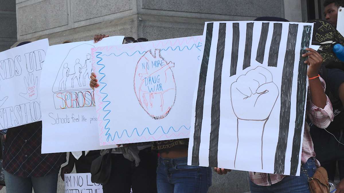 Students from Mighty Writers South hold their posters high on the North Broad Street side of City Hall. (Emily Scott / WHYY)