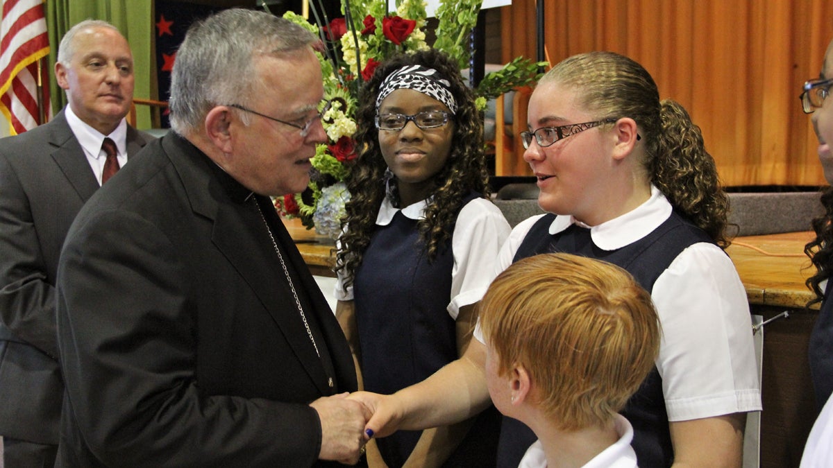 a  Archbishop Charles Chaput talks with St. Gabriel Elementary School students (from left) Amirah Drew, Caitlin Dwyer, and Joseph McCann after announcing that their school and 13 others will be independently run. (Emma Lee/for NewsWorks)