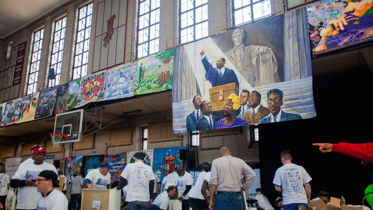 Underneath murals of Martin Luther King and other civil rights leaders volunteers worked on buidling bookshelves at Girard College on Martin Luther King Day. (Brad Larrison for NewsWorks)