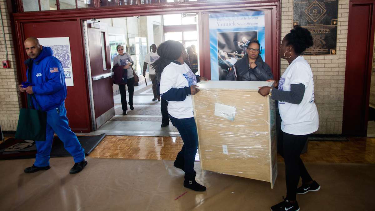 Volunteers with the literacy organization Read By 4th carried newly built bookshelves to be loaded on to trucks. (Brad Larrison for NewsWorks)