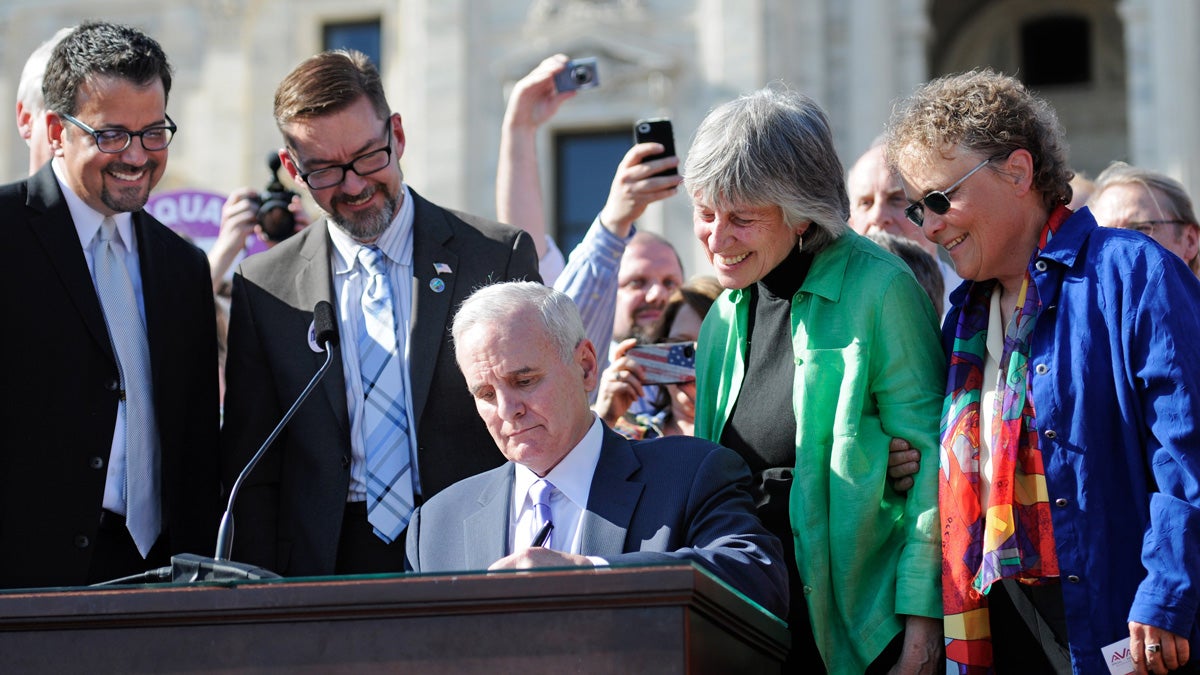 Minn. Governor Mark Dayton signs the state's same-sex marriage bill into law in front of the Capitol in Saint Paul on Tuesday as bill authors Sen. Scott Dibble, second from left, with his partner Richard Leyva, and Rep. Karen Clark, second from right, and her partner Jacqueline Zitaduring, look on. (Craig Lassig/AP Images for Human Rights Campaign) 