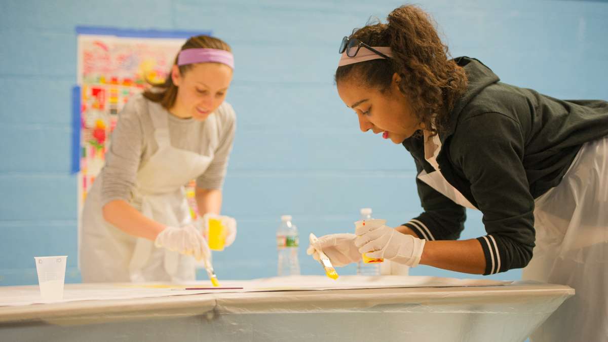 Amanda DeSenna (left) and Marielle Fortune paint one of the mural’s canvas squares.