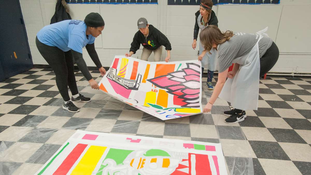 Completed mural squares are laid on a sheet of plastic for temporary storage by (from left) Meniyah Miller, Alex Kim, mural artist Shira Walinsky, and Ann Kramer.