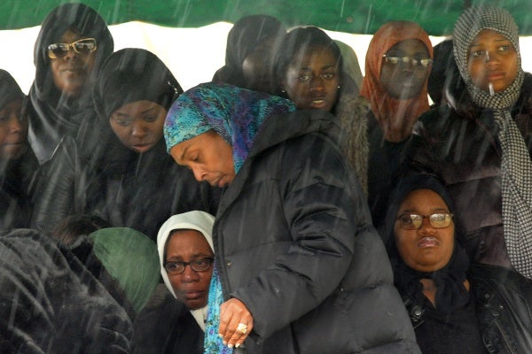 <p><p>Rain begins to fall at the gravesite as Leslie Glenn, left, sits with Najji's fiancée Lashawn Brown, right, who is six months pregnant. Funeral director Khadijah Alderman, foreground, attends to the burial. (Peter Tobia/for NewsWorks)</p></p>
