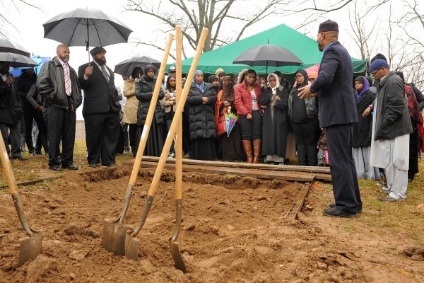 <p><p>At the end of the burial rite, family and friends gather around the gravesite, and Iman Kenneth Nuriddin shares a departing prayer. (Peter Tobia/for NewsWorks)</p></p>
