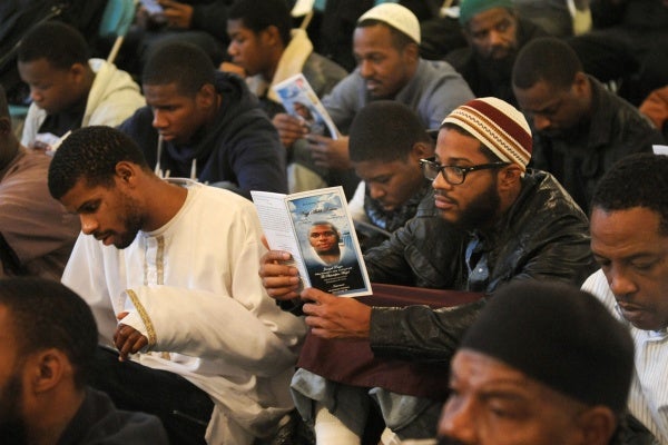 <p><p>Attendees waiting for the service to start read the funeral program. (Peter Tobia/for NewsWorks)</p></p>
