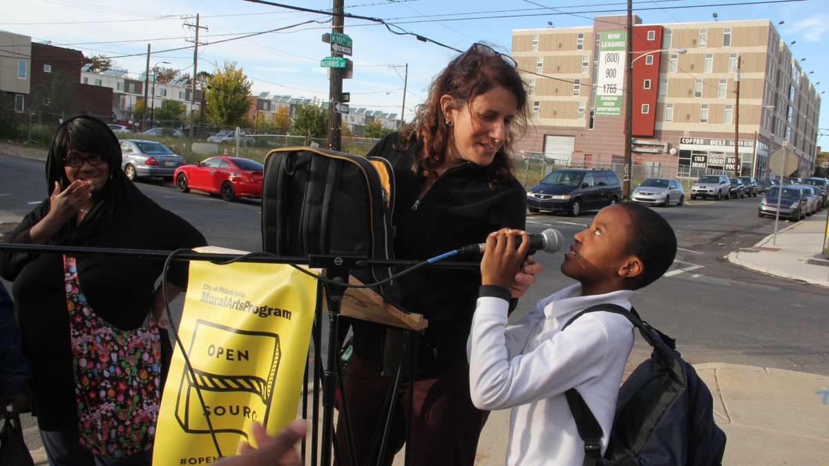 A young Norris Homes resident steals the show during a mural dedication ceremony. Artist Jennie Shanker worked with residents to memorialize the homes, which will be razed and rebuilt. Another phase of her Open Source project will document what happens to members of the community as it disperses. (Emma Lee/WHYY)