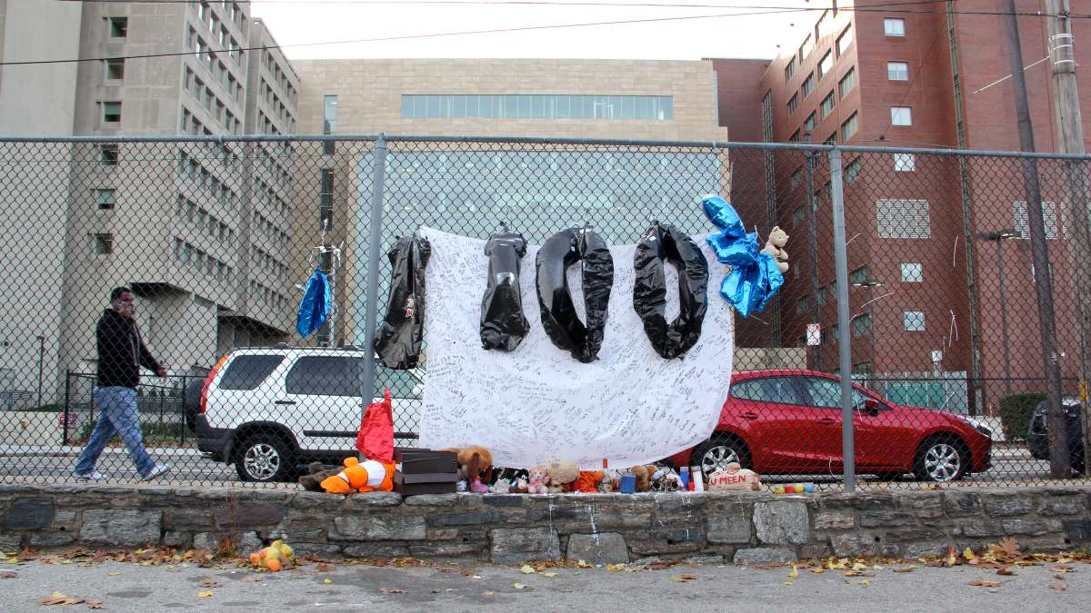 A memorial to a former Norris Homes resident who died of a drug overdose hangs from the fence around the housing project's playground and basketball court, opposite Temple University's Science Education and Research Center. (Emma Lee/WHYY)