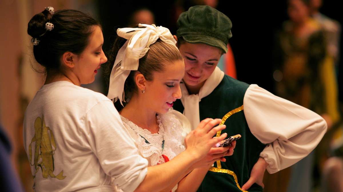 Ballerinas unwind before the performance, sharing things on their phones. (Nathaniel Hamilton/for Newsworks)