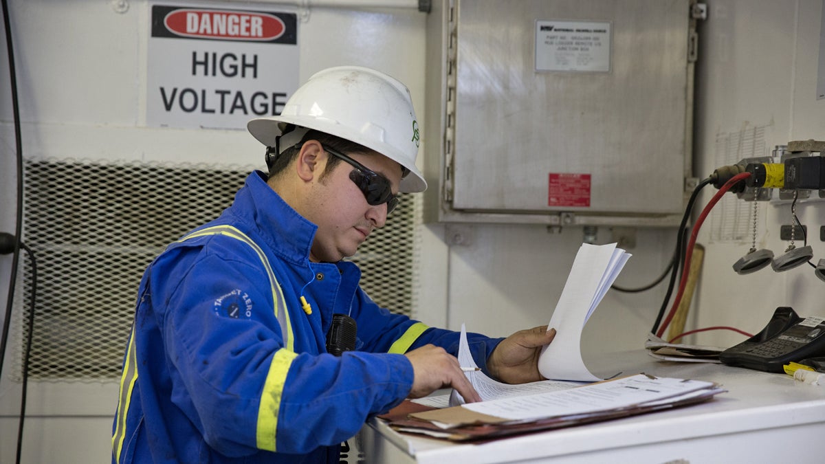  A worker checks paperwork on the monkey board of a Cabot Oil & Gas drill rig in Kingsley, Pa.  (Lindsay Lazarski/WHYY)  