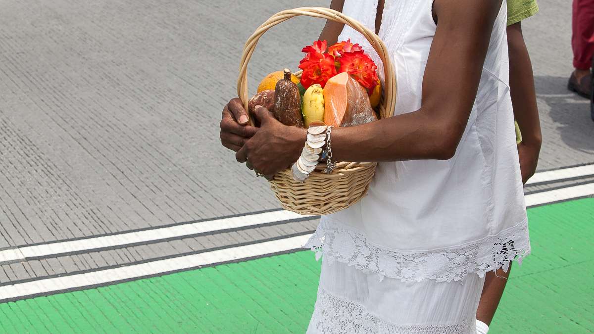 A woman carries offerings for Oshun, the Yoruba goddess of the river, during a procession to launch the Odunde Festival, a 39-year tradition in Southwest Center City. (Brad Larrison/for NewsWorks)