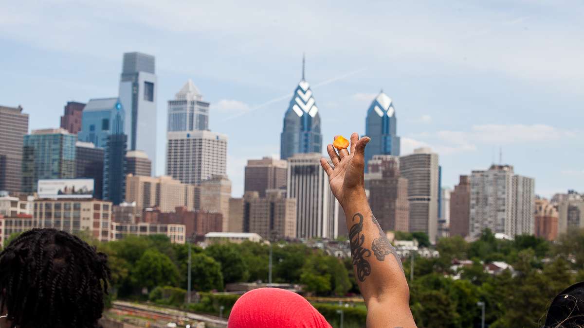 Fruit and flowers are offered to the Yoruba godess of the river from the South Street Bridge during the Odunde Festival.  (Brad Larrison/for NewsWorks)