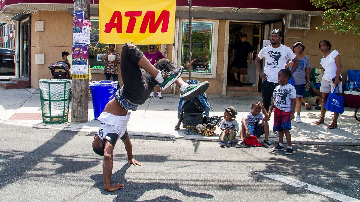 Dante Thompson of the Crowd Pleaserz group break dances at the corner of Bainbridge and Grays Ferry Avenue during the Odunde Festival. The festival blends African cultural heritage with modern African American culture. (Brad Larrison/for NewsWorks)