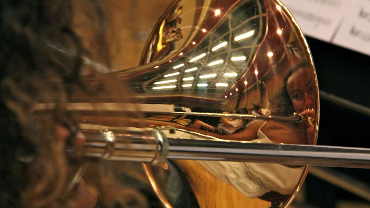 Masterman High School's Ariannis Hines is reflected in the bell of her trombone as she rehearses with the All City Orchestra.(Emma Lee/WHYY)