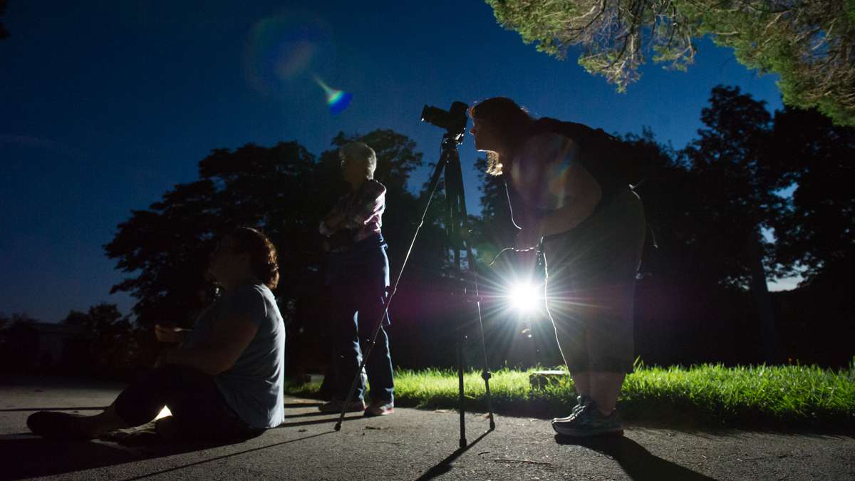 After dark, a photographer composes her subject.