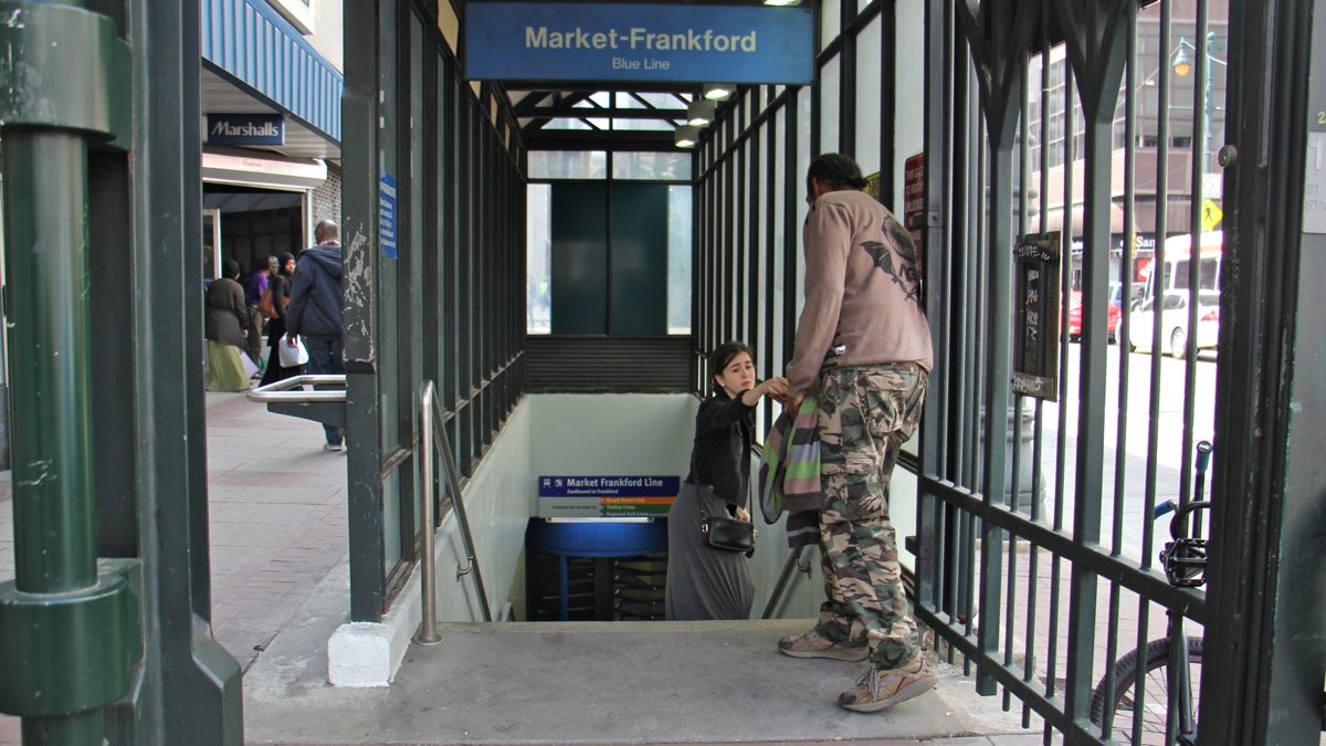  A SEPTA rider stops to give some change to a man panhandling outside the 11th Street station. (Emma Lee/WHYY) 