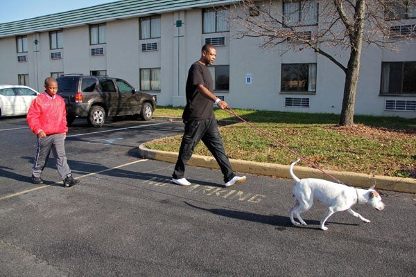 <p>Isaiah Generette and his stepfather Edward Veney take their dog, Dream, for a walk outside the Motel 6 in Swedesboro, where they have been staying since their Paulsboro home was evacuated because of a chemical spill. (Emma Lee/for NewsWorks)</p>

