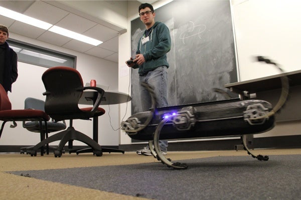 <p>Penn student Justin Starr controls a hexapedal robot. Inspired by insect movement, the six-legged robot can move over uneven terrain. (Emma Lee/for NewsWorks)</p>
