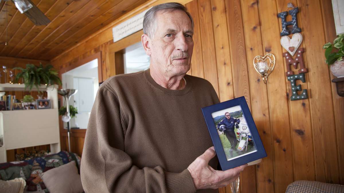 Jim Rosipal, 70, a retired Monroeville police officer, with a photograph of himself in his 40s, when he was part of the motorcycle division. (Irina Zhorov/WESA)