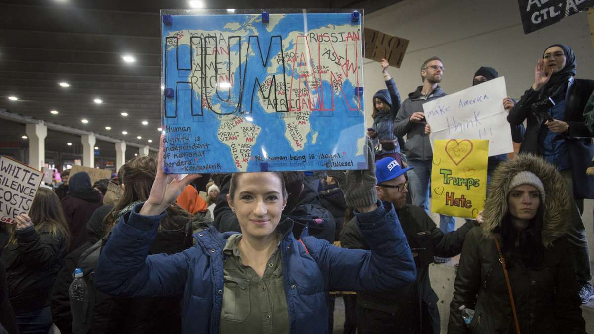 Ashley Woodruff of Philadelphia holds a sign she made over a year earlier in a class on immigration law at her university. (Branden Eastwood for NewsWorks) 