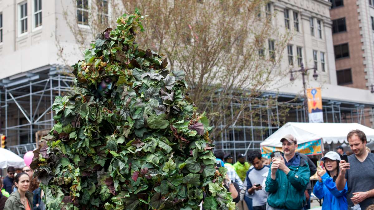 Actors on stilts and covered in plants walk around the 2016 PIFA Street Fair on South Broad Street.