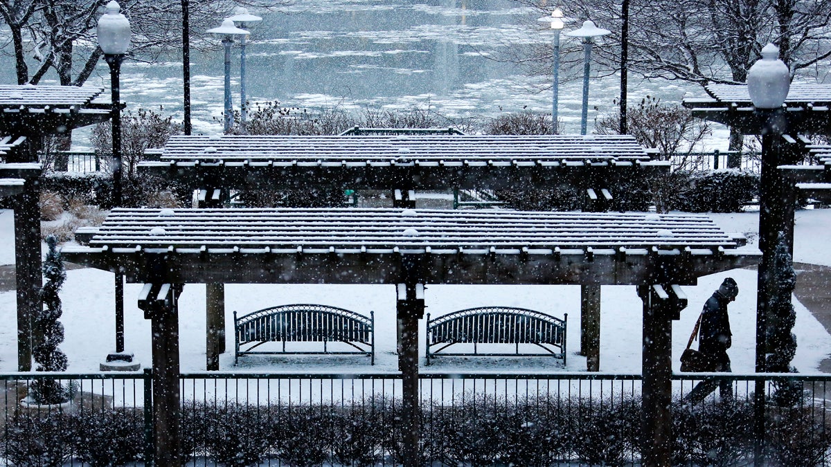 Snow falls on a park overlooking the Allegheny River in downtown Pittsburgh during evening rush hour Wednesday