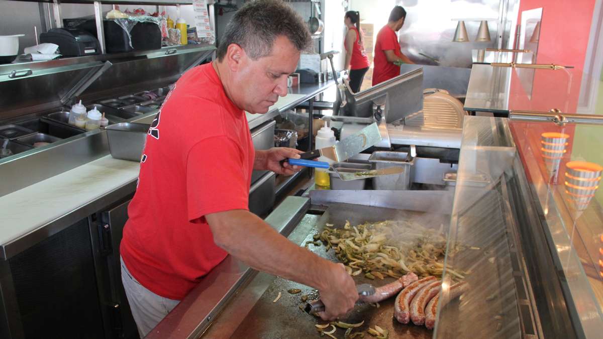 John Spadavecchia throws some onions and sausages on the griddle at Johnny Fries in Ortley Beach. The restaurant is doing a brisk business serving the contractors who are working overtime to repair Sandy damage. (Emma Lee/for NewsWorks)