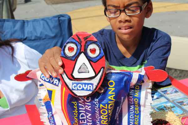 Johnny shows his grandmother’s work. As a visual artist and educator, Andria Morales uses recycled materials, in this case a Goya rice bag, to create small “Vejigantes”, traditional Puerto Rican masks.  (Elisabeth Perez-Luna/WHYY)
