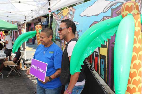 After waiting in line, two friends pose in front of a tropical-like back drop for a photo at the Philly Te Ama, Philly Loves You tourism booth. The photos are immediately sent to their e-mails. No waiting for that. (Elisabeth Perez-Luna)