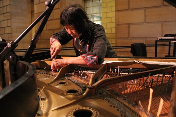 <p>John Cage's music for prepared piano gets its unusual sounds from objects placed between the strings. Margaret Leng Tan prepares a piano at the Philadelphia Museum of Art before her performance of Cage's music for films. (Emma Lee/for NewsWorks)</p>
