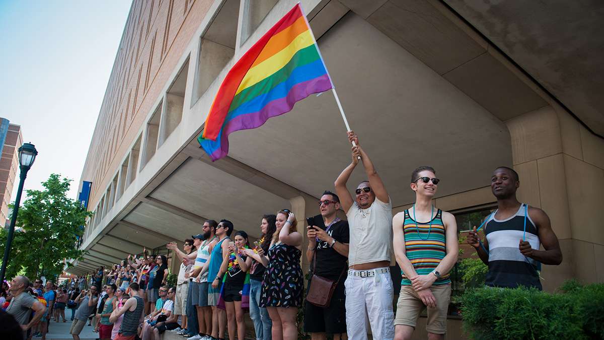 Pride festival goers wave the rainbow flag from along the parade route in Philadelphia. (Branden Eastwood for NewsWorks)