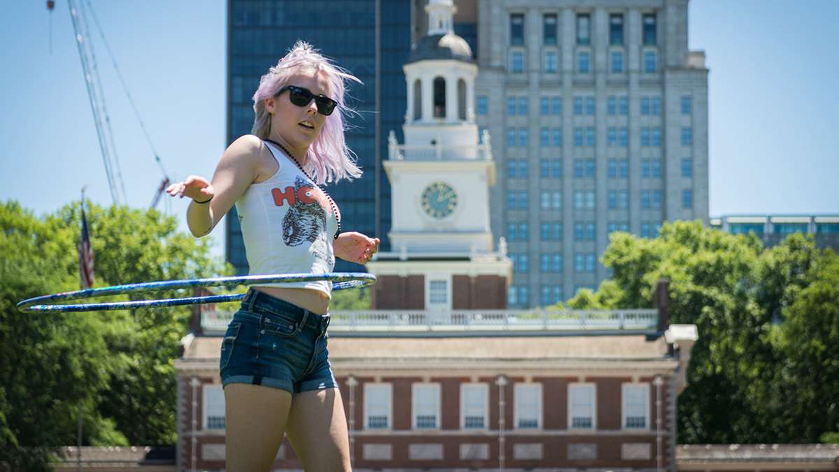 Katie Schwald dances with a hula hoop in front on independence hall at Philadelphia Pride Parade and Festival. (Branden Eastwood for NewsWorks)