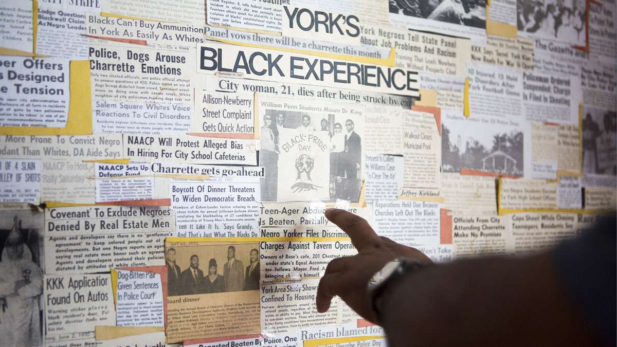 Kirkland, 68, a history researcher who founded the newly formed Historical African American Preservation Society, points to an article in a collage of news clips hanging in his home in York, Pennsylvania. (Jessica Kourkounis/For Keystone Crossroads)