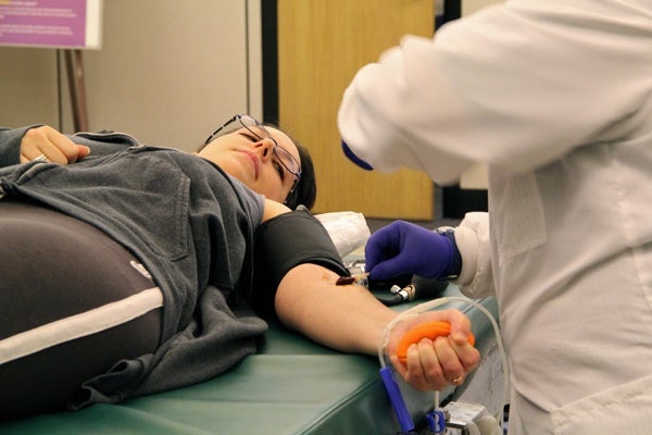 <p>Orli Gal of Philadelphia squeezes a rubber ball as she donates a pint of blood at the American Red Cross donation center. (Emma Lee/for Newsworks)</p>
