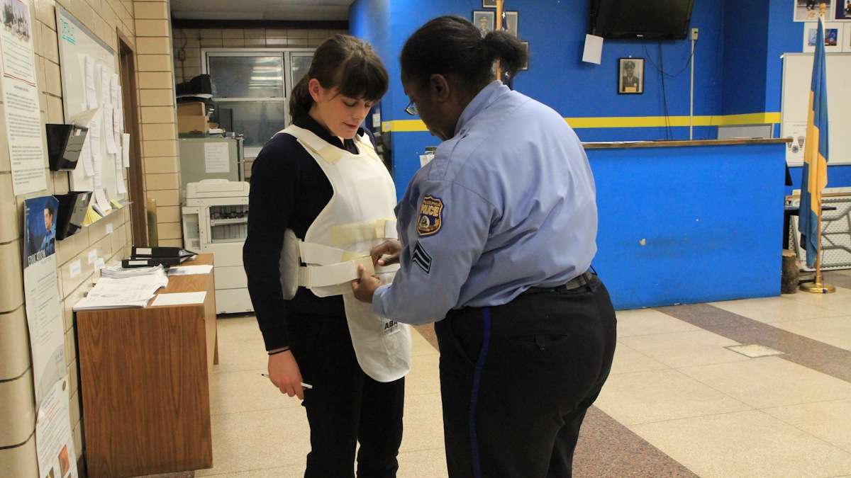 WHYY Urban Life Correspondent Elizabeth Fiedler straps on a bulletproof vest for her ride-along with police in South Philadelphia. (Kimberly Paynter/WHYY)