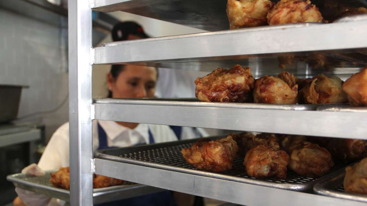 Patricia Martinez sets up shelves of fried chicken at Federal Donuts. (Emma Lee/WHYY)
