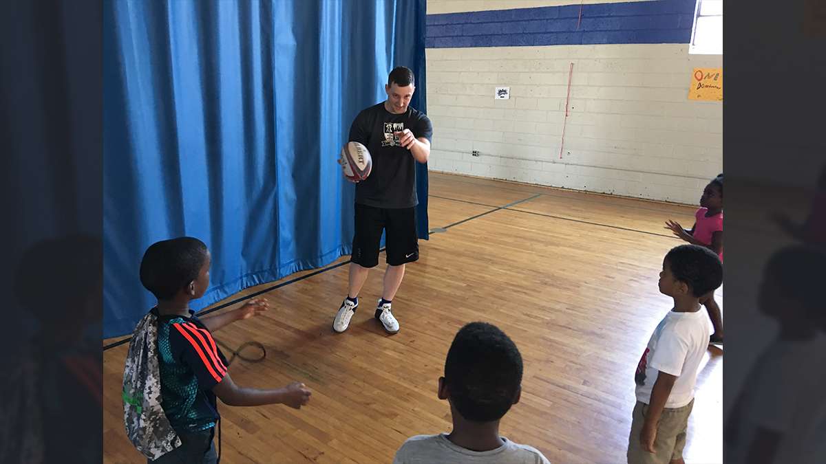 Program coordinator Dave Codell teaches a lesson on passing during a Rugby camp at the Northeast Frankford Boys & Girls Club (Jay Scott Smith/WHYY)