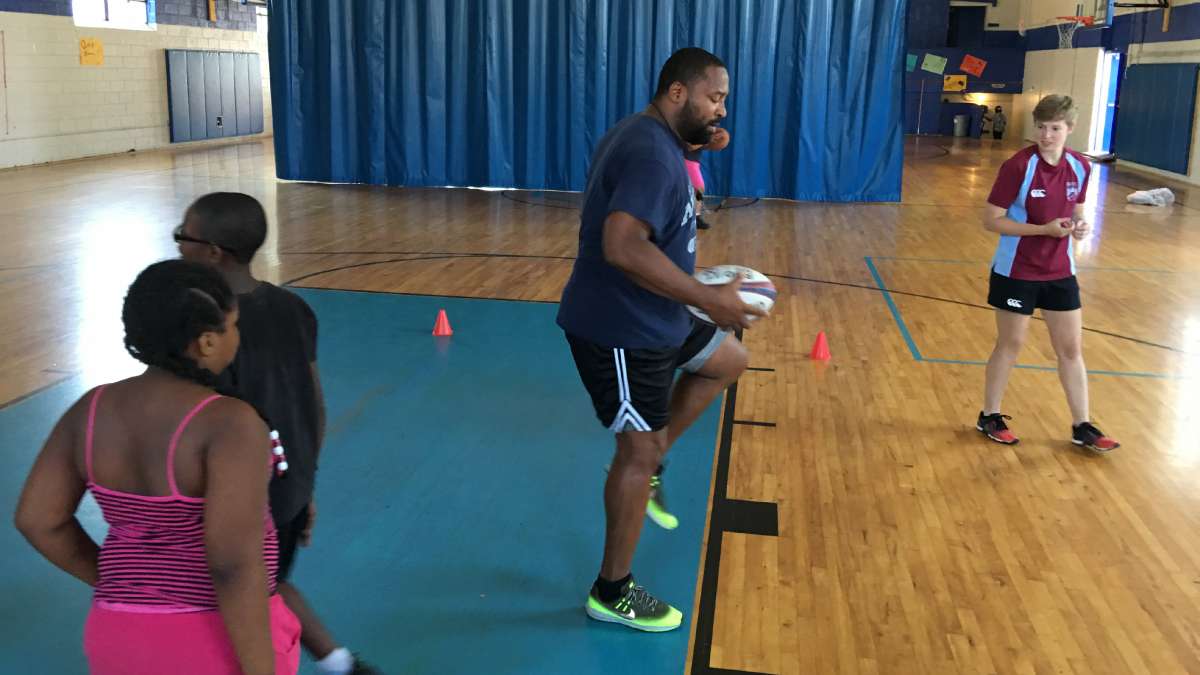 Rugby coach James Brunson demonstrates footwork to a group of kids during a Rugby camp at the Boys and Girls Club in North Frankford. (Jay Scott Smith/Newsworks)