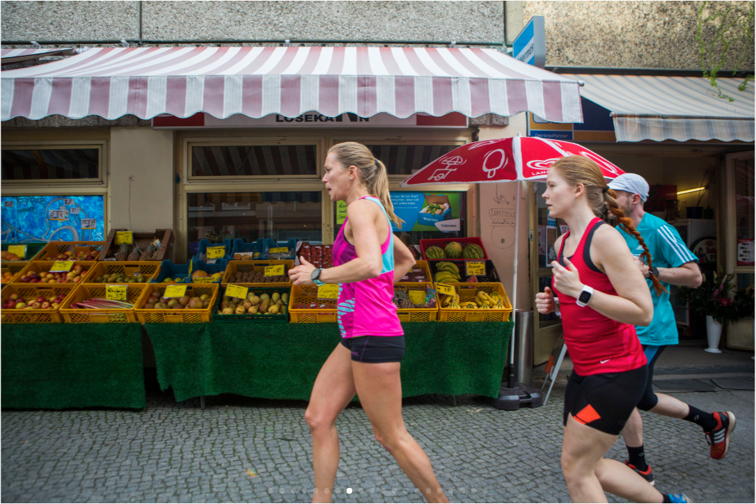 A running club jogs past a quiet fruit stand on the wealthier side of Mitte’s social divide. (Jessica Kourkounis/For Keystone Crossroads)