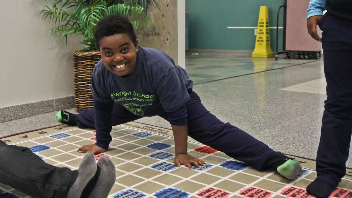 Nathaniel Rapley, 9, takes a break from playing to stretch on the scrabble rug. (Kimberly Paynter/WHYY)