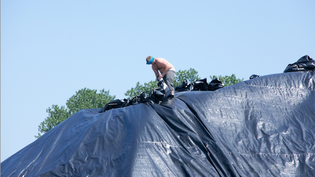  A worker installs black protective tarps during this hot summer heat in Camden, N.J. (Nat Hamilton/for NewsWorks) 