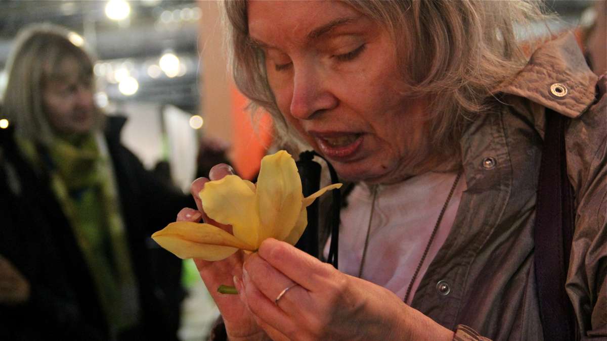 Carla McCollaum examines a yellow orchid through smell and touch during a sensory tour for the blind at the Philadelphia Flower Show.