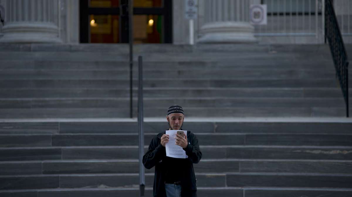 Ahead of the Oct. 24, 2016, sentencing of Former Pennsylvania Attorney General Kathleen Kane, Jonathan Lee Riches, is seen taking a photo of a courtroom public pass, as he stands on the steps of Montgomery County Court House, in Norristown, Pennsylvania. (Emma Lee/WHYY)